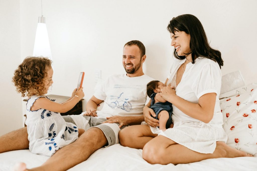 Parents and children talking and laughing sitting on a bed