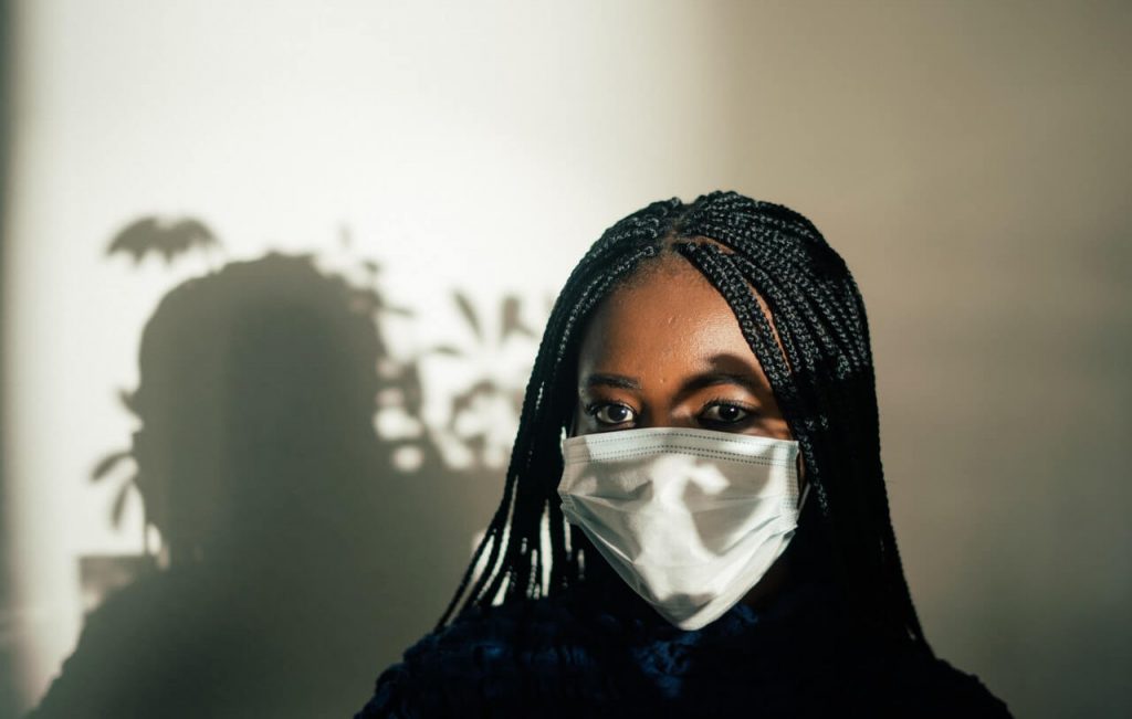 Black woman in mask with sunlight falling on face
