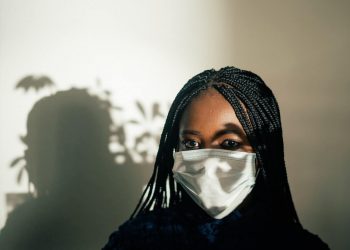 Black woman in mask with sunlight falling on face