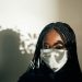 Black woman in mask with sunlight falling on face