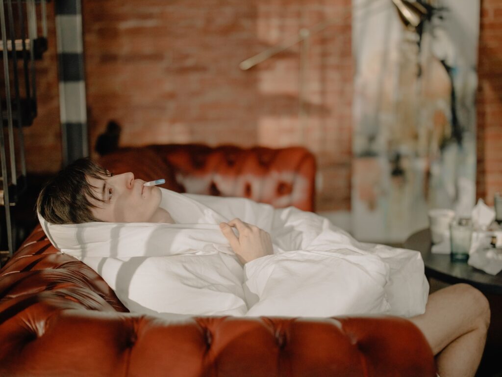 A sick person lying on bed covered with white blanket