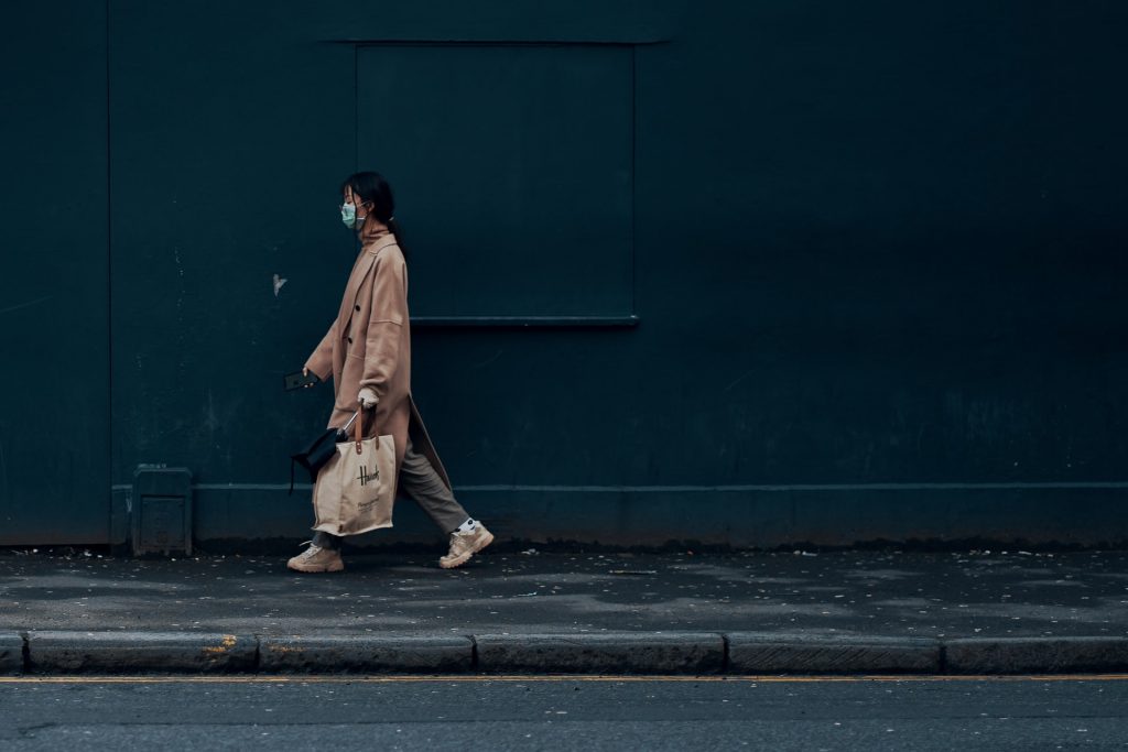 woman walking on footpath wearing mask