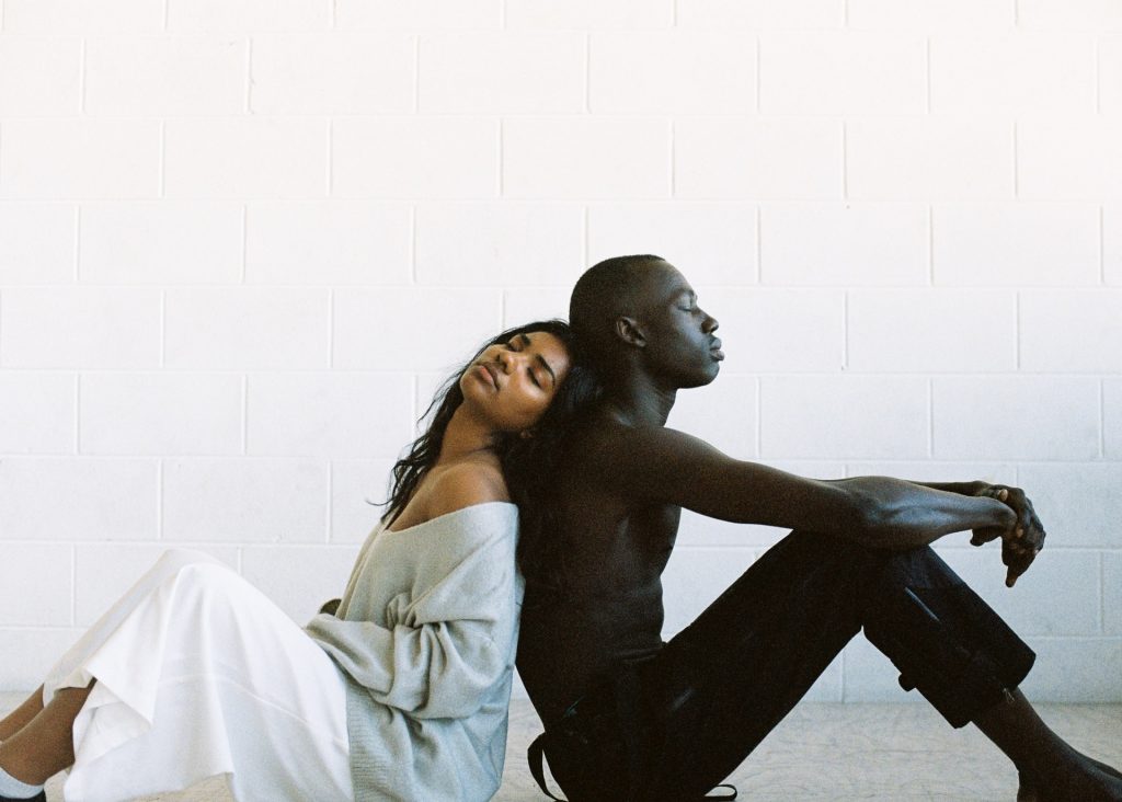 Black man and woman sitting back to back feeling depressed