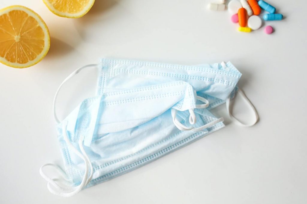 Face masks, medicines, and lemon slices on a white background