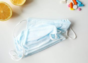 Face masks, medicines, and lemon slices on a white background