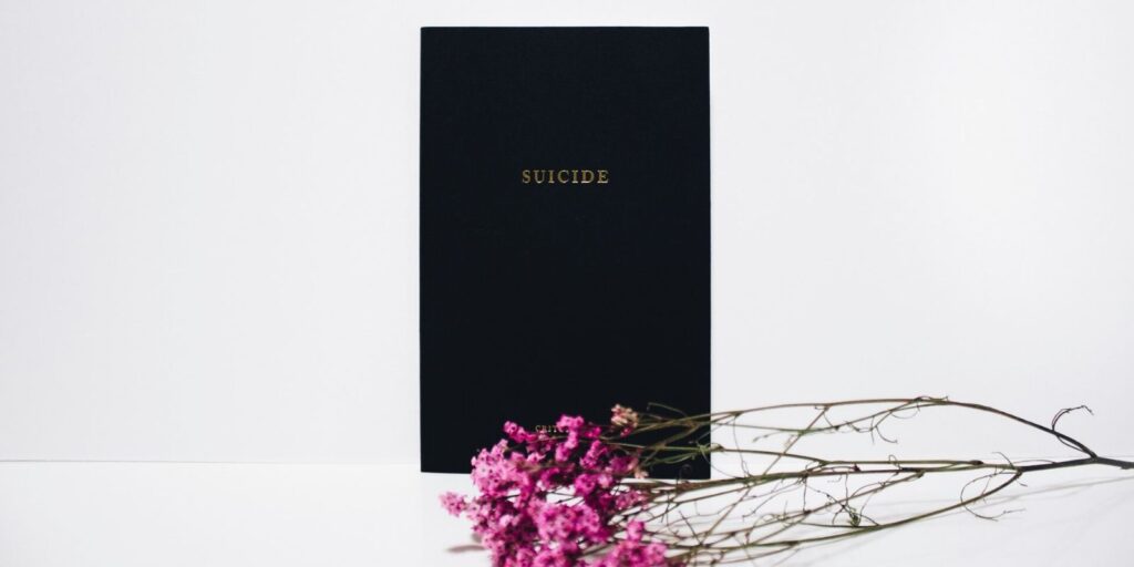 A black background with note of suicide and purple flowers