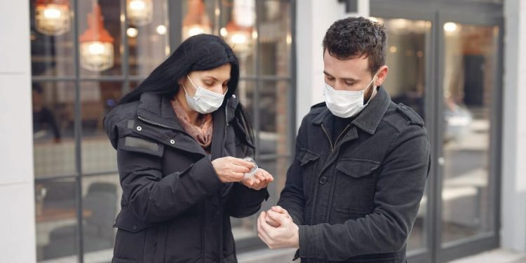 CDC Response Team Says Coronavirus Cases Rates Higher Than Reported 1 Image of Young couple wearing masks disinfecting hands