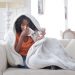 Coronavirus Symptoms Persist For Three Weeks, Says CDC 8 Image of a young ethnic woman sitting on sofa having coronavirus symptoms of flu and body chills