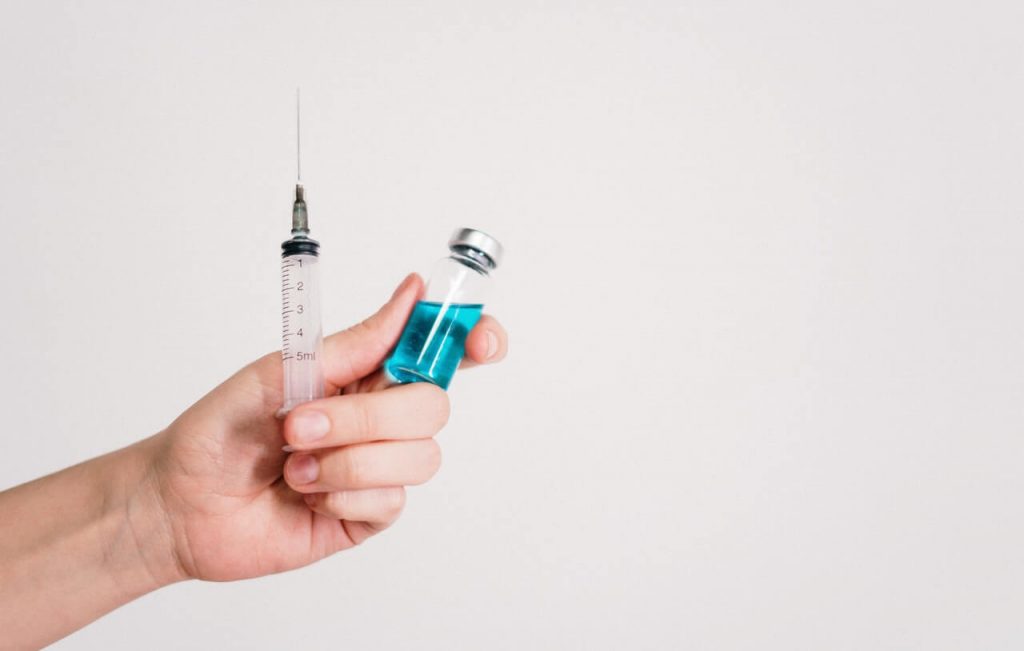 Doctor hands holding COVID-19 vaccine and injection