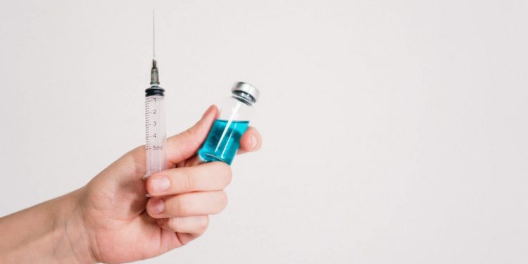 Potential COVID-19 Vaccines Move Towards Final Testing Phase 1 Doctor hands holding COVID-19 vaccine and injection