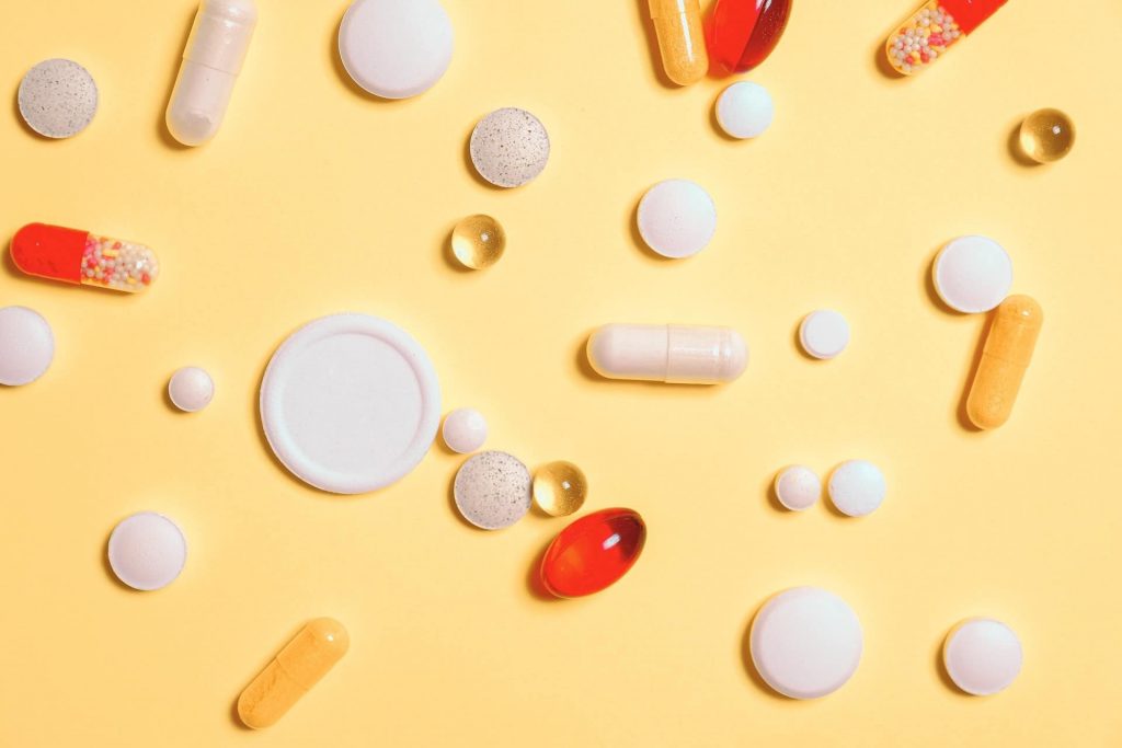 White, red, orange, and transparent pills on a light orange background