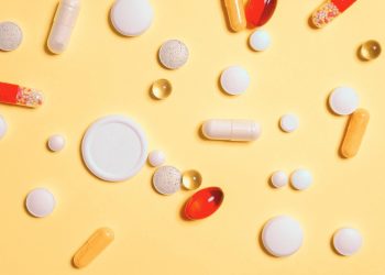 White, red, orange, and transparent pills on a light orange background