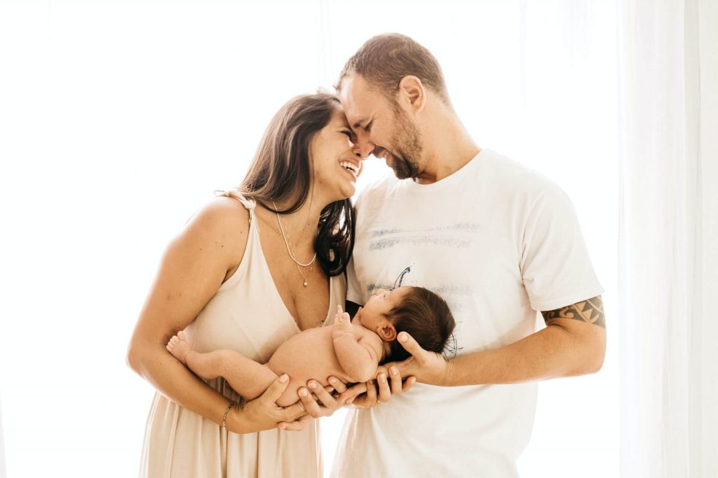 Image of Mother and father holding newborn baby and laughing