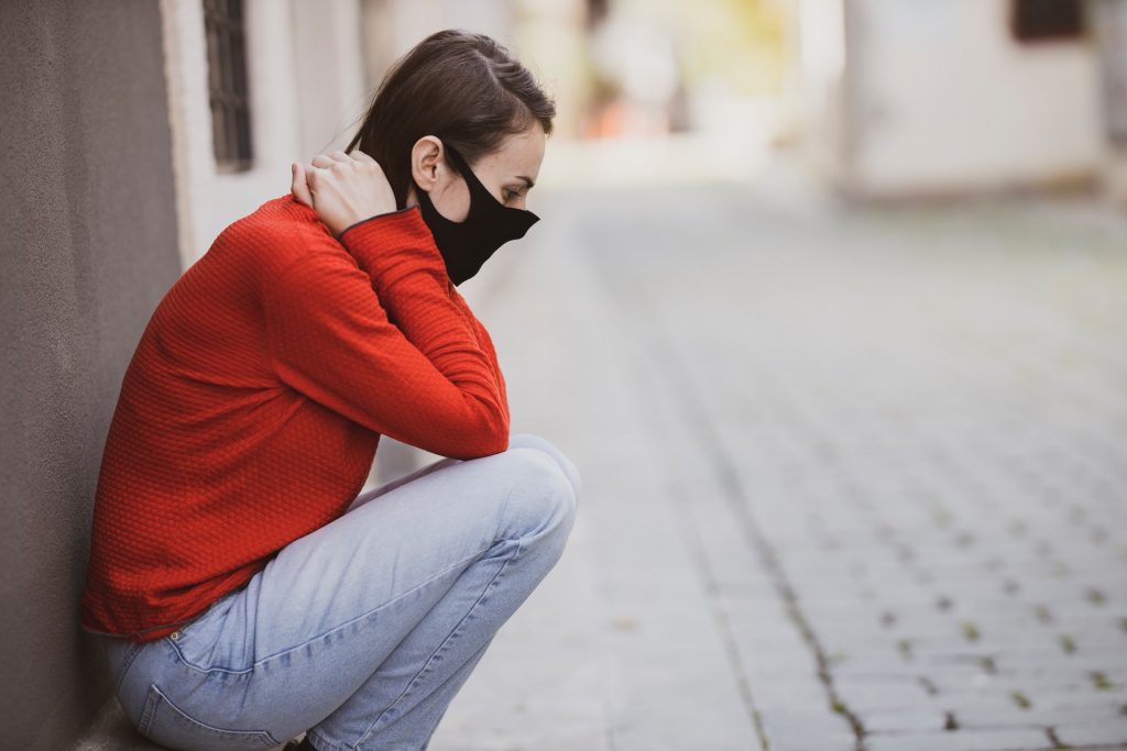Woman sitting on a footpath feeling distressed