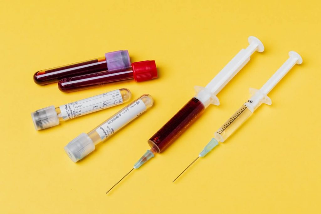 Syringes and blood test tube samples on a yellow background