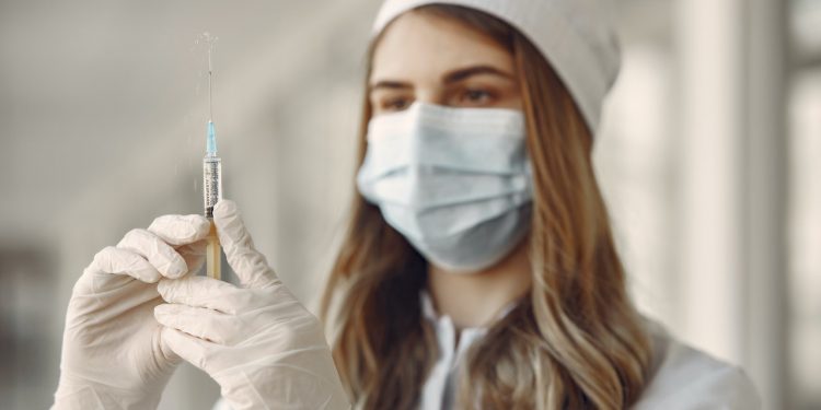 MMR Vaccine Could Prevent COVID-19 Symptoms 1 Doctor holding a vaccine syringe