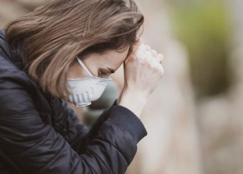 Image of a woman feeling fatigue and wearing mask