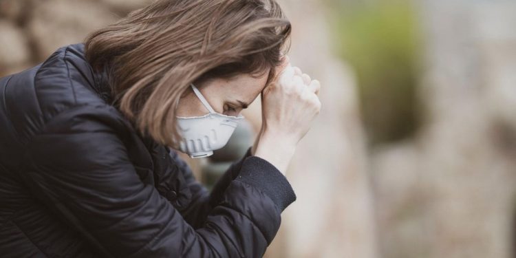 Image of a woman feeling fatigue and wearing mask