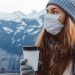Image of a Woman wearing warm clothes and mask in winters holding a coffee cup