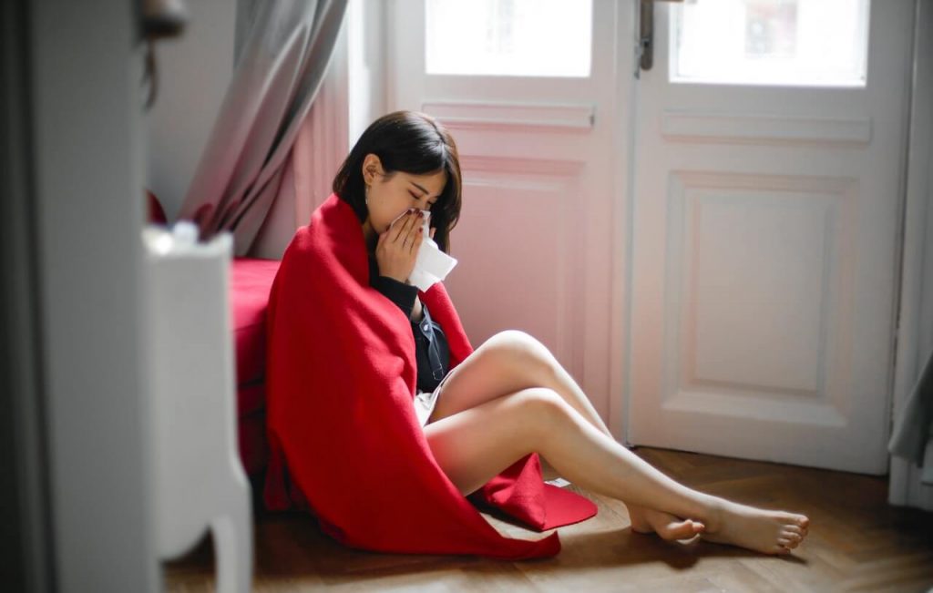 Woman having flu sitting on floor