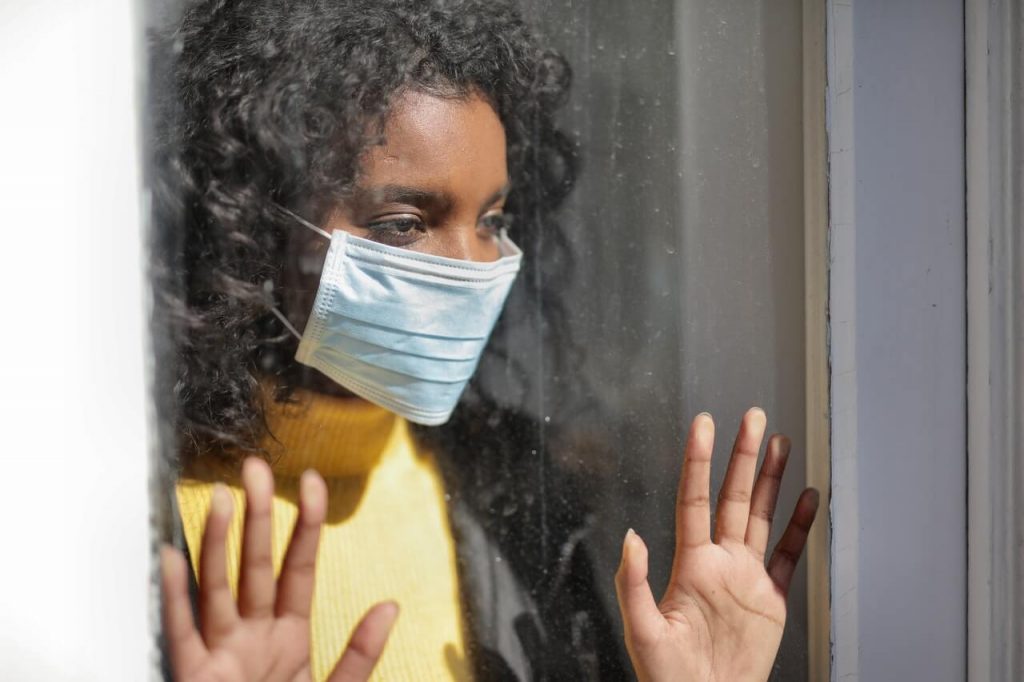 A serious young ethnic woman at home wearing medical mask