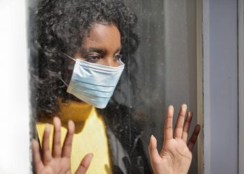 A serious young ethnic woman at home wearing medical mask