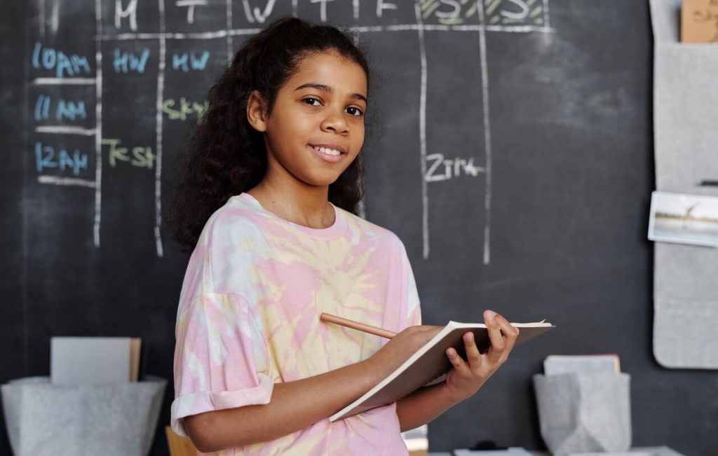 Young girl in school holding notepad and pencil
