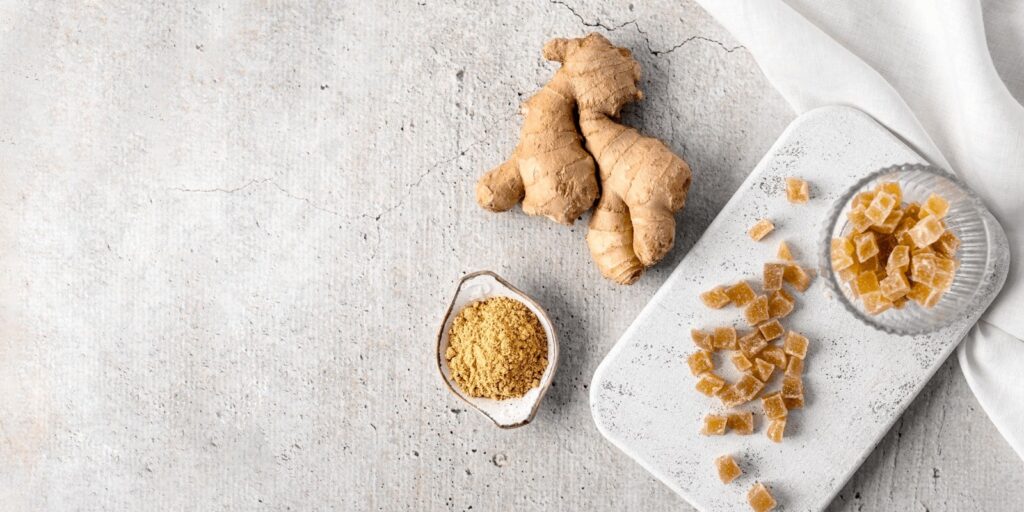 Ginger root, crumbs, and ginger powder on a grayish white surface