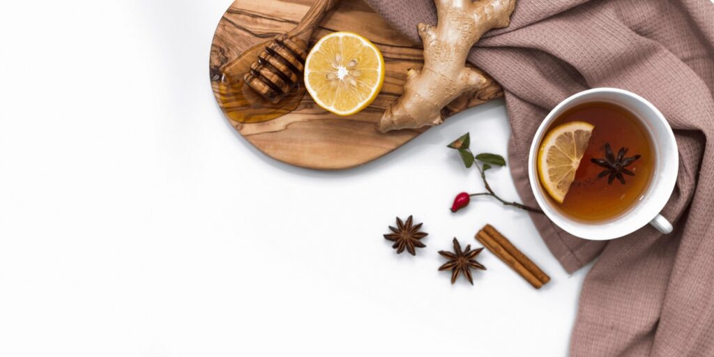 Ginger tea with ginger root, lemon, and honey with a brown cloth on white background