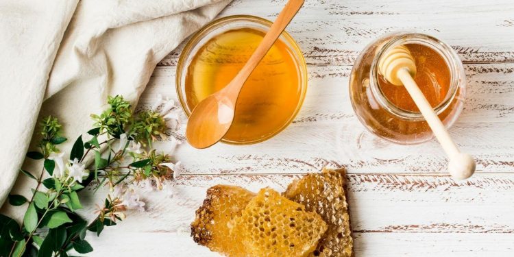 Honey Beats Antibiotics For Treatment Of Cough And Cold 1 Image of Honey jar with honeycomb on a solid surface with herbs