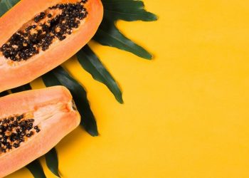 Papaya Fruit: Health Benefits and Nutritional Components 13 Image of Papaya fruit with green leaf on a bright yellow background