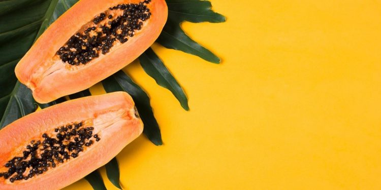Papaya Fruit: Health Benefits and Nutritional Components 1 Image of Papaya fruit with green leaf on a bright yellow background