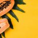 Image of Papaya fruit with green leaf on a bright yellow background