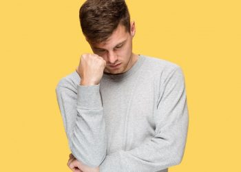Stress: Types, Causes, Symptoms, And Management 28 Image of a young man in stress standing across a yellow wall