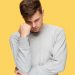 Stress: Types, Causes, Symptoms, And Management 8 Image of a young man in stress standing across a yellow wall