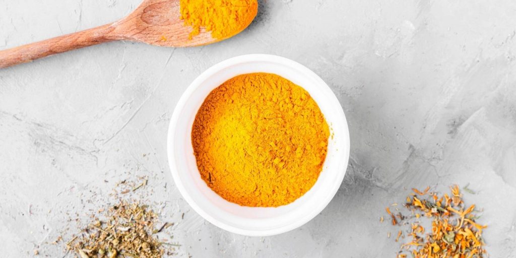 Turmeric powder in white bowl on a marble background