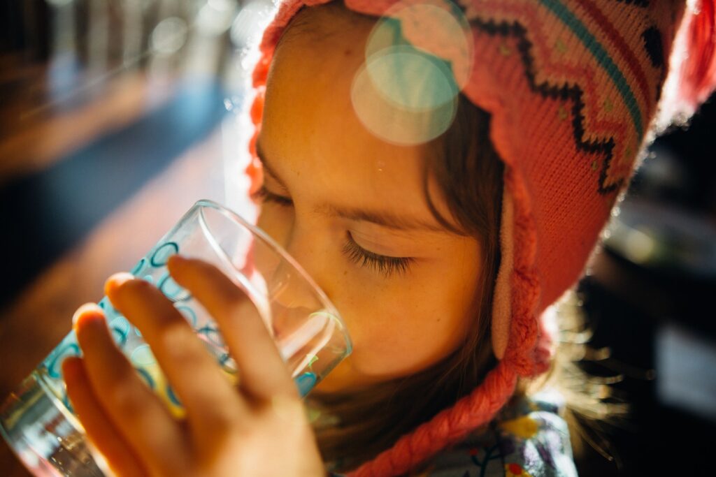 A little girl drinking water from a glass