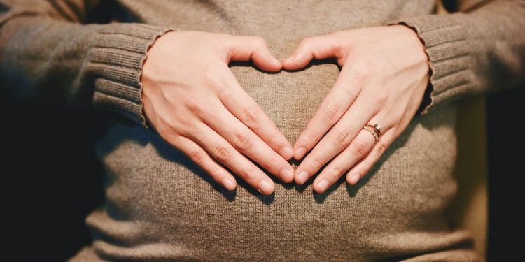 A pregnant woman putting hands on her belly